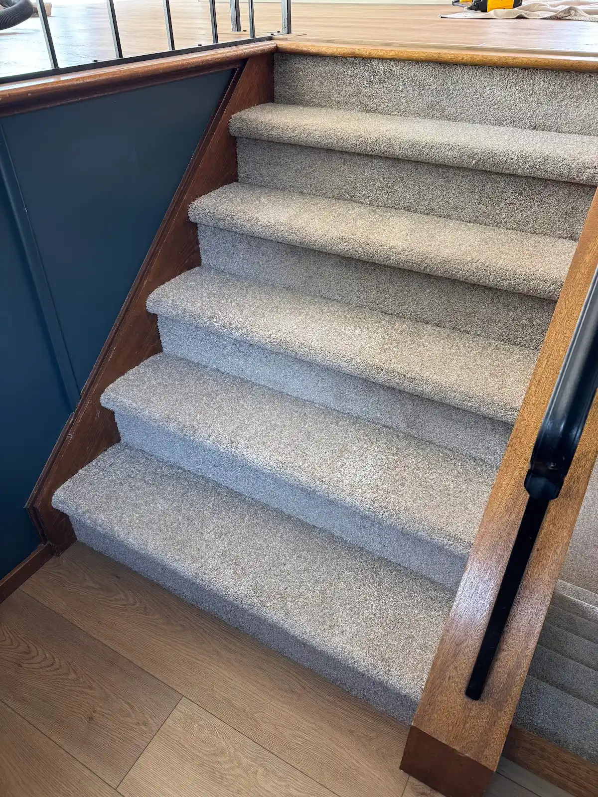 Fresh gray carpet on a staircase framed by stained oak railings