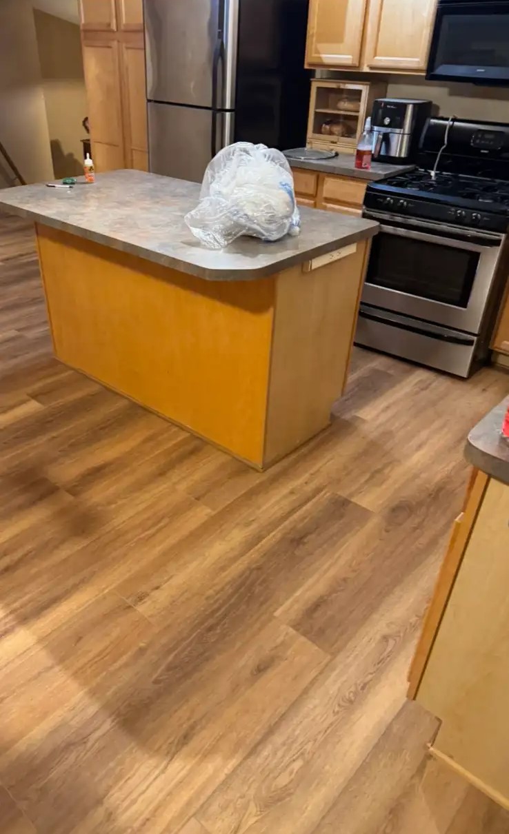 Warm wood-look luxury vinyl plank installed around a kitchen island